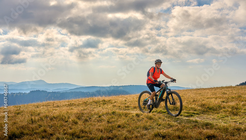 nice senior woman on her electric mountain bike cycling on Feldberg summit, top of German Black forest