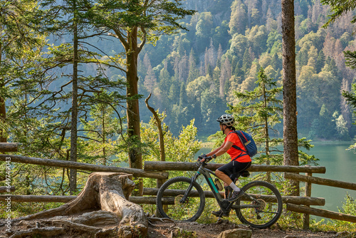 nice senior woman on her electric mountain bike cycling Lake Feldsee in the German Black Forest near Titisee-Neustadt, Baden-Württemberg, Germany