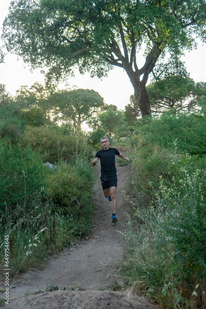 Experienced trail runner with gray hair and sleek black gear, conquering rugged terrain. Experienced trail runner with gray hair and sleek black gear, conquering rugged terrain.