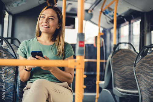 Lifestyle portrait of a young businesswoman sitting with smart phone at the modern train. Woman on a cellphone in public transport.