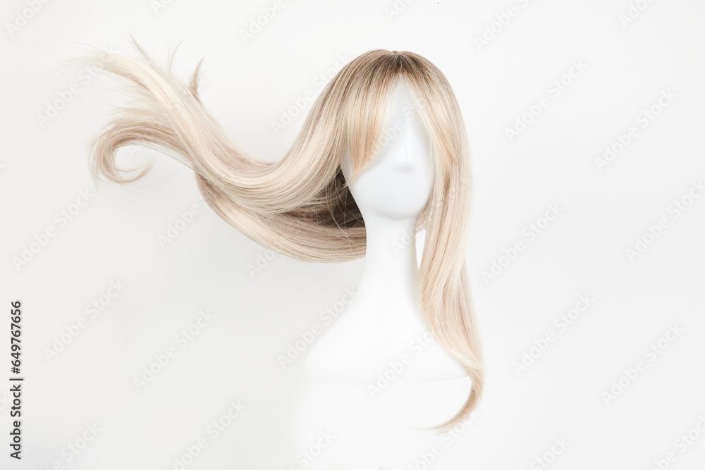 Natural looking blonde wig on white mannequin head. Long hair on the plastic wig holder isolated on white background, front view.