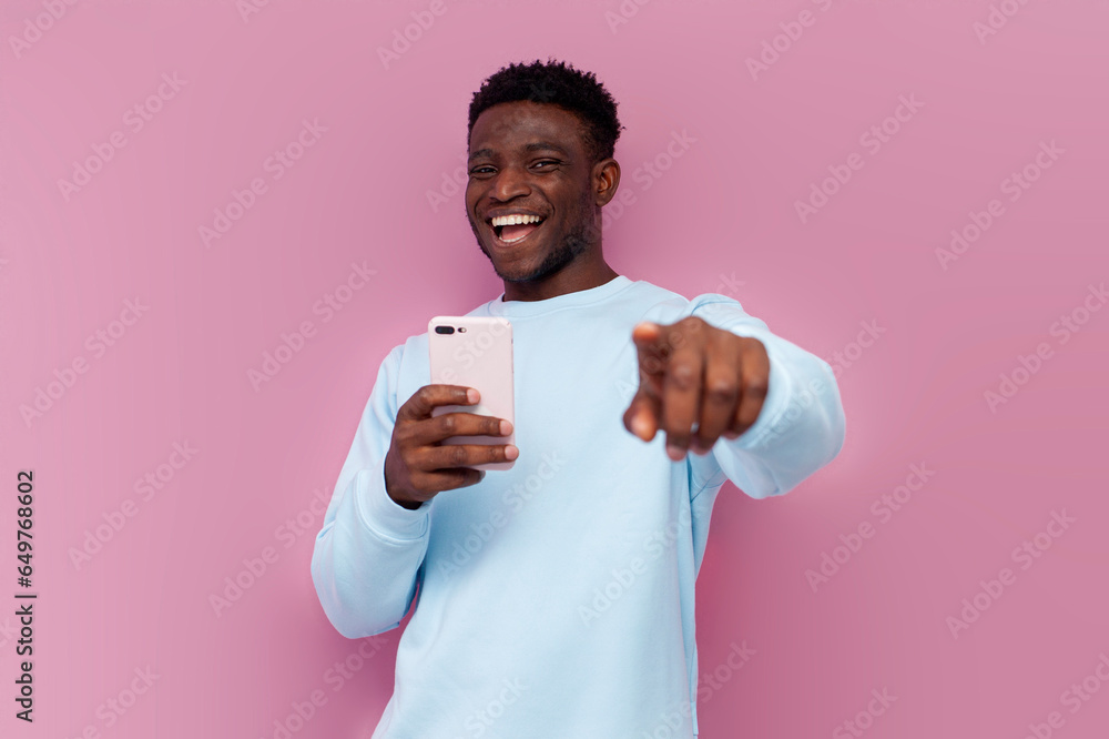 I choose you. african american man using smartphone laughing and pointing with his hand at the camera I choose you. african american man using smartphone laughing and pointing with his hand at the camera