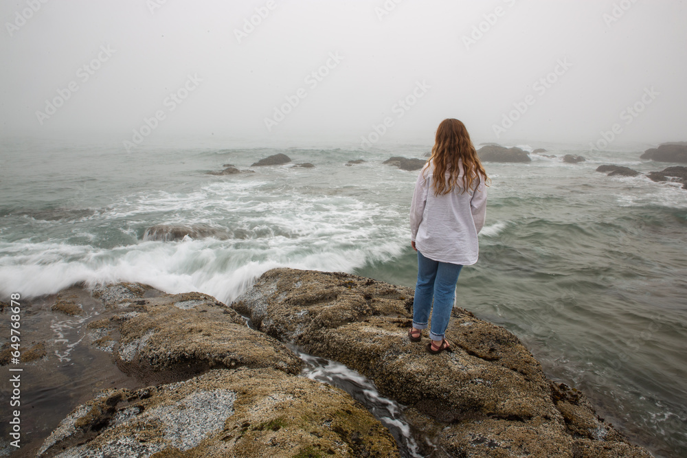 young redhead woman standing on a rock on the Oregon Pacific ocean coast
