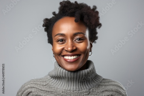 Joyful young woman with curly hair, smiling and looking at camera on gray background
