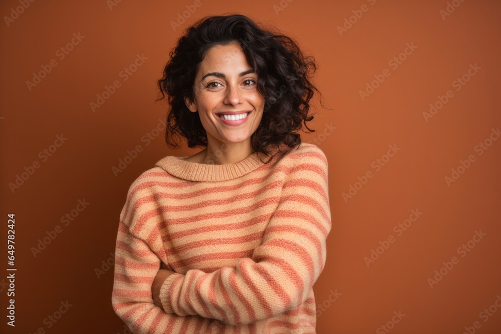 Smiling woman with curly hair in red sweater on colored background