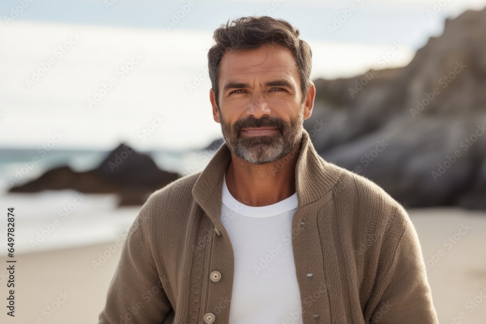 Happiness by the sea: Mature man with beard and sweater smiling, looking at camera with nature as the backdrop