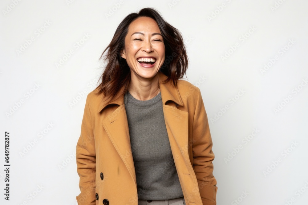 Joyful woman with curly hair and white jacket smiling at camera in studio