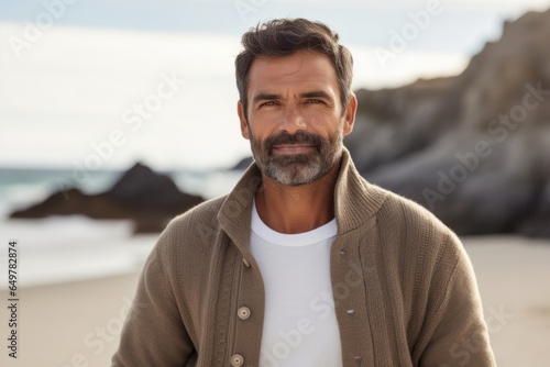 Obraz na płótnie Happiness by the sea: Mature man with beard and sweater smiling, looking at camera with nature as the backdrop w salonie