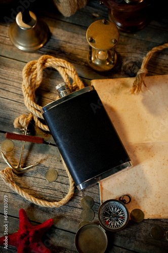 Treasure island concept on a wooden table background. Black flask on sailor or pirate table between different marine atributes and treasure