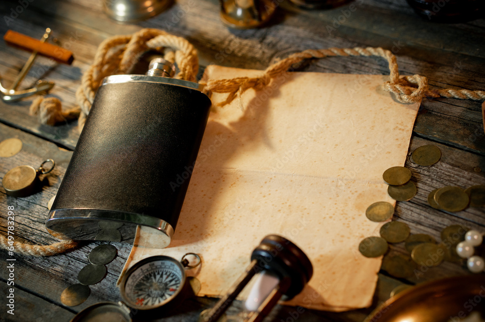 Treasure island concept on a wooden table background. Black flask on sailor or pirate table between different marine atributes and treasure