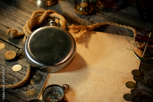 Metal flask with a sheet of paper for text or map. Treasure island concept on a wooden table background
