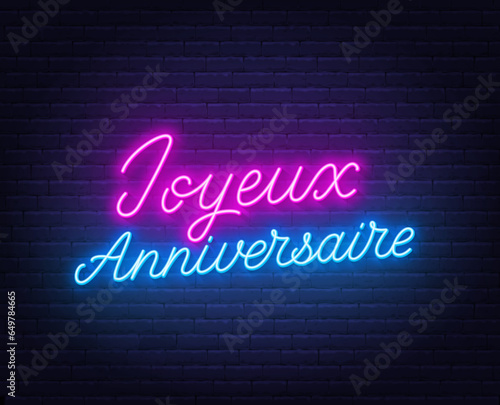 Joyeux Anniversaire neon lettering on brick wall background.