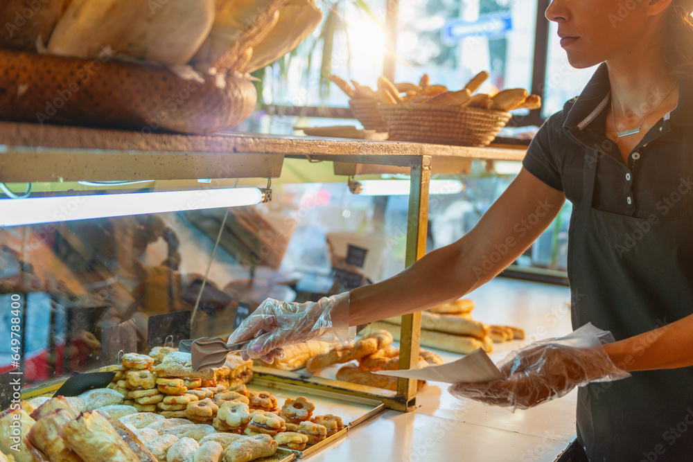 Female baker carefully arranges an assortment of delicious pastries in a charming bakery shop.