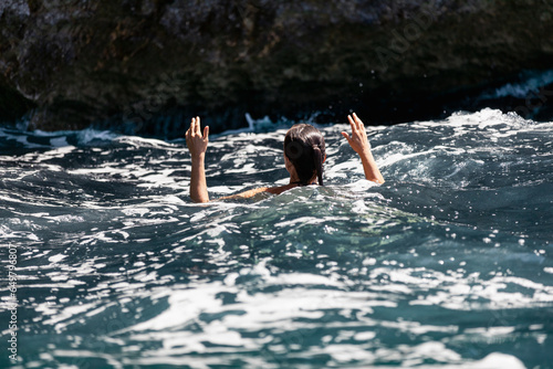 Women swimming in the ocean, trying to keep the hands dry. 