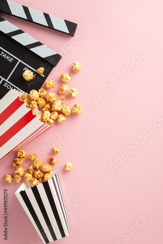Cinematic Treats: vertical top view shot of popcorn, and a clapperboard on pastel pink, setting the stage for a delightful movie night with friends