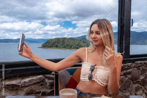 VIDEO CALL FROM CELL PHONE. WOMAN TAKING A SELPHIE IN LAGUNA DE LA COCHA CAFERERIA photo