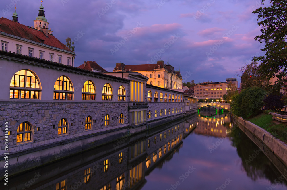 Obraz na płótnie Sunrise landscape view of ancient city center of Ljubljana. Embankment of Ljubljanica River with illuminated colorful historic houses. Tavel and tourism concept w salonie