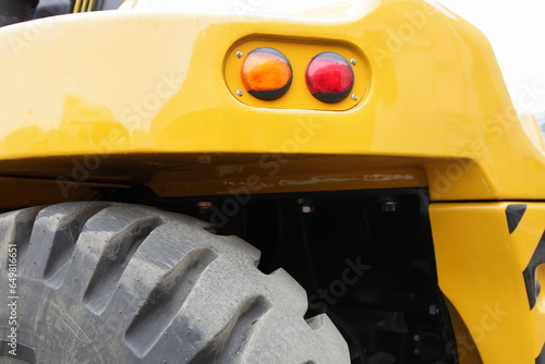 Big wheel and tail lights on board of yellow heavy forklift truck