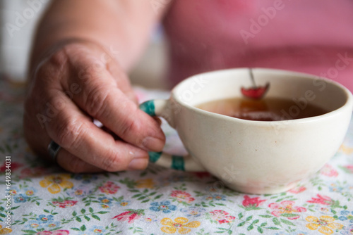 Manos de mujer mayor sosteniendo una taza de té photo