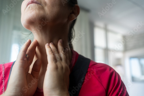 Endocrine system. Woman doing thyroid self examination indoors, closeup
