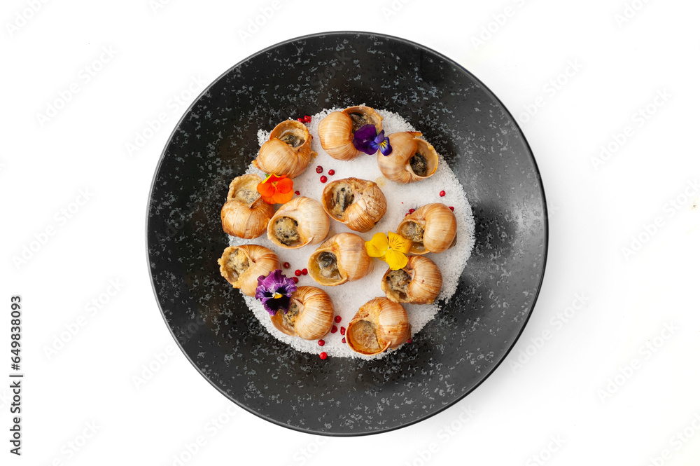 Cooked grape snails in shells on a black plate isolated Cooked grape snails in shells on a black plate isolated