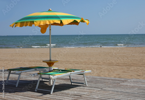Fototapeta Naklejka Na Ścianę i Meble -  yellow and green sunshade and deckchair in the beach
