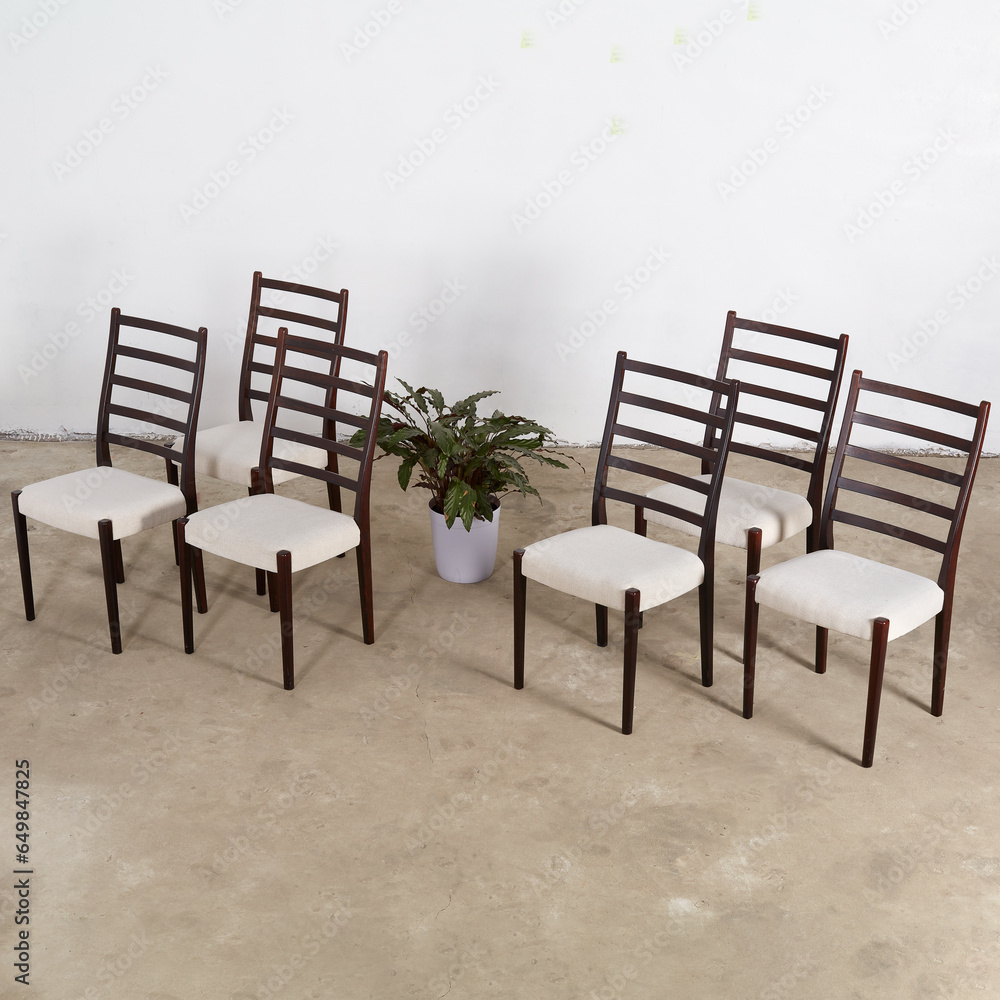 Set of elegant Mid-Century Modern rosewood dining chairs. Vintage dark wood ladderback chairs. Interior photograph. Set of elegant Mid-Century Modern rosewood dining chairs. Vintage dark wood ladderback chairs. Interior photograph.