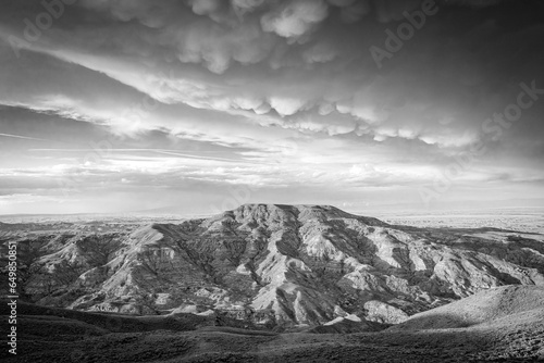 Retro black and white image of a butte in the northwest landscape of Wyoming with storm clouds overhead.