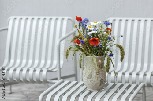 Wild flower bouquet (Cornflowers, chamomiles wheat and poppies) in terracotta vase. Wildflower and grass varieties.
