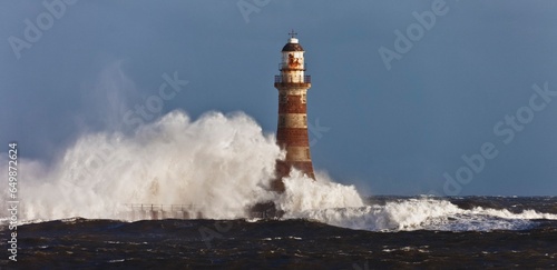 Waves Crashing Against A Lighthouse; Sunderland, Tyne And Wear, England photo