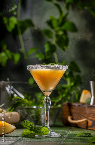 Melon margarita cocktail with mint in glass on dark green ceramic tile background