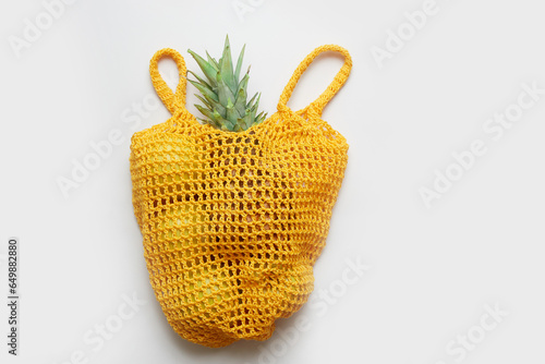 Green salad and fruits in yelloy eco string bag on white background. The view from the top. photo