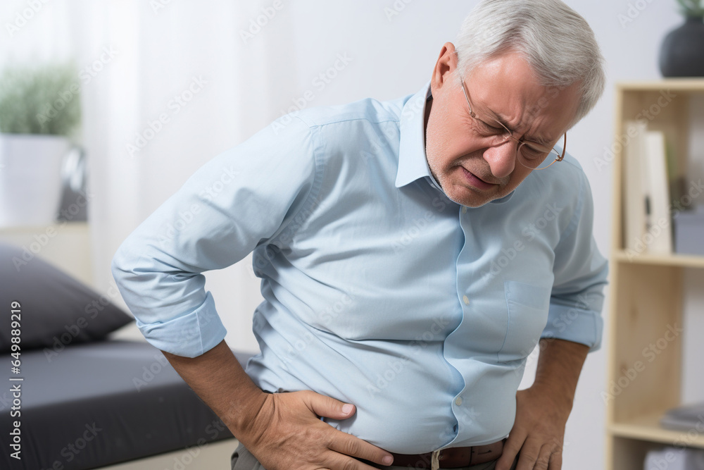 An elderly man holds his stomach in pain.