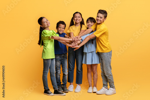 Happy multiracial school aged kids holding hands top each other