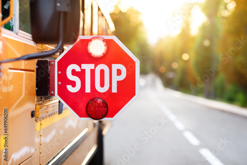 Canvas Print Yellow school bus with red stop sign standing on the road