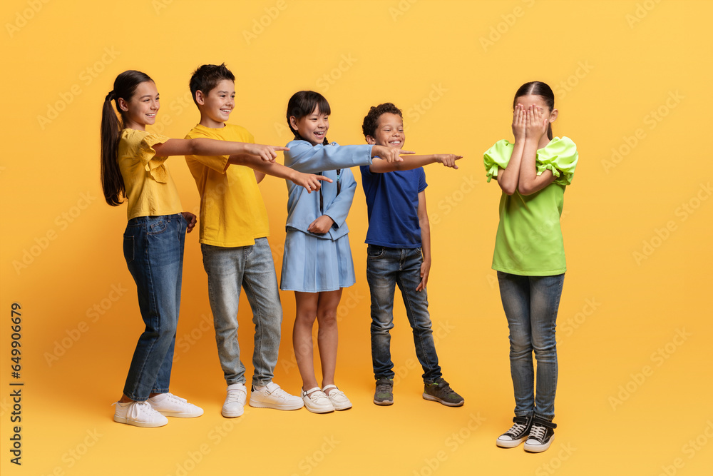 Fototapeta premium Multiracial laughing preteen kids pointing at crying girl