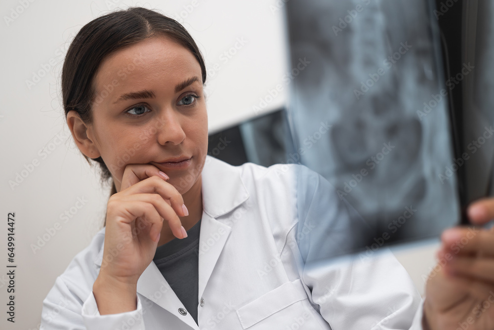 close up of doctor worried looks at radiological X-ray film to evaluate the patient's condition as part of medical healthcare. close up of doctor worried looks at radiological X-ray film to evaluate the patient's condition as part of medical healthcare.
