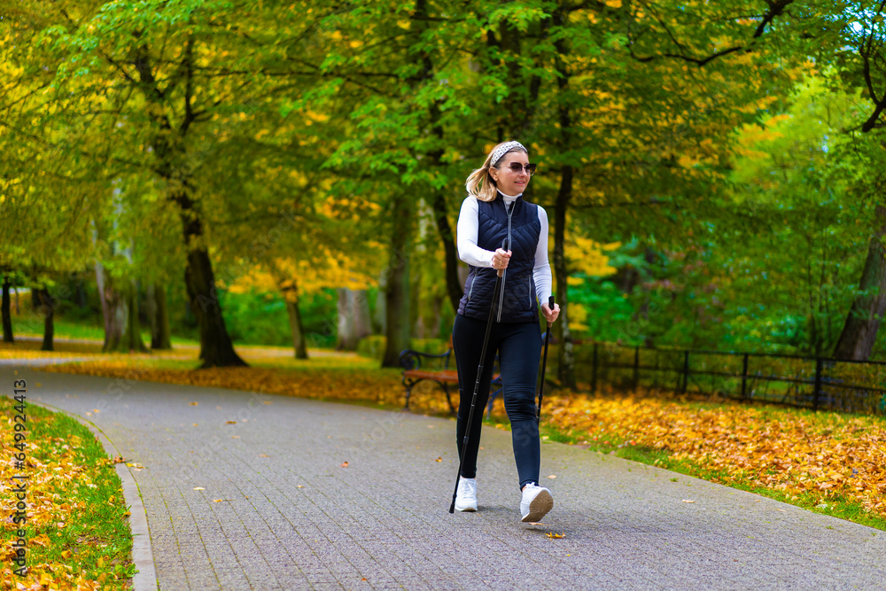 Fototapeta premium Nordic walking - woman exercising in city park 