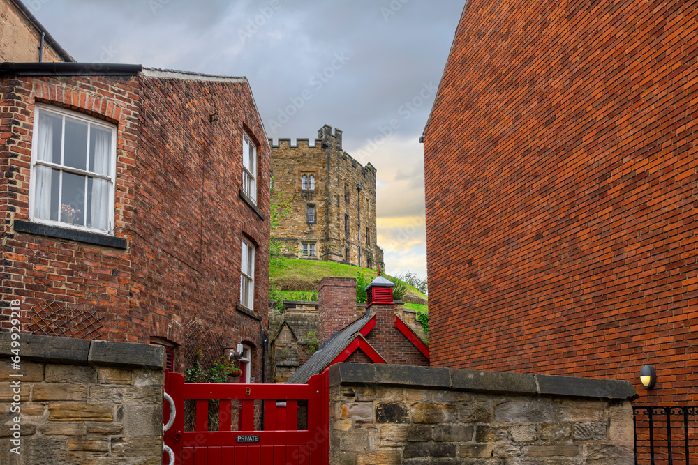 Φωτογραφία The main tower of the medieval Durham castle, an 11th century Norman hilltop castle, can be seen from between historic brick buildings in the town of Durham, England, UK