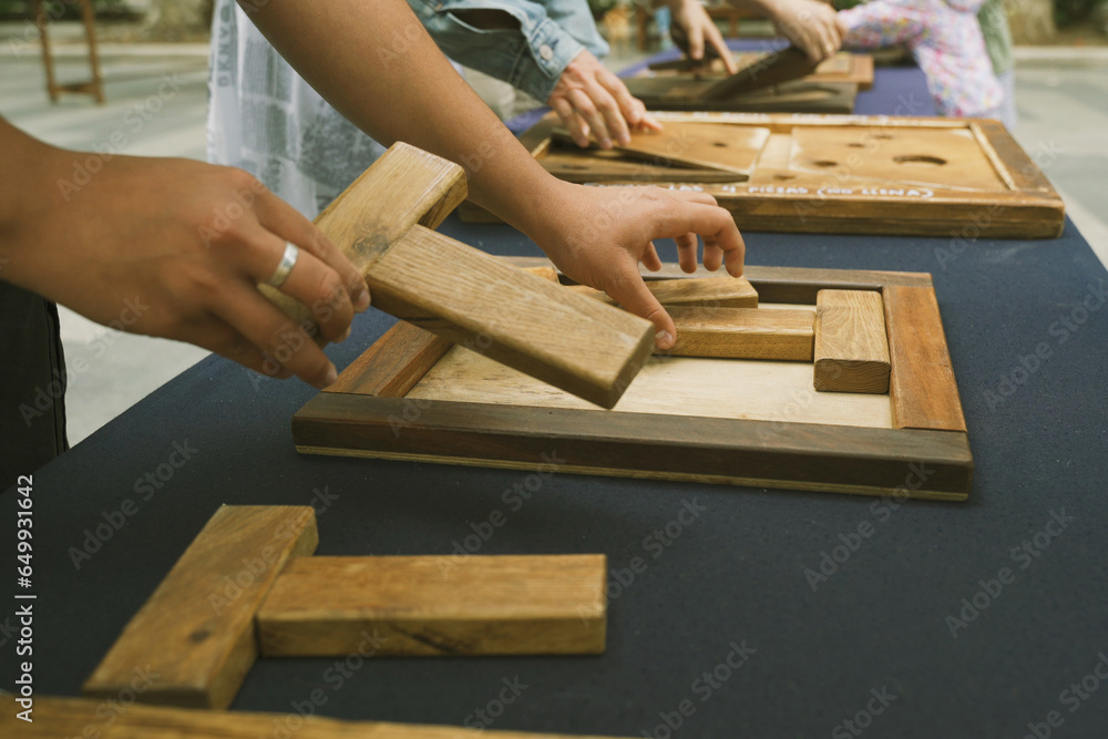 Children collect wooden puzzles on the street in the park. Children collect wooden puzzles on the street in the park.