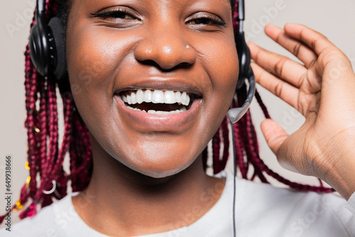 Happy smiley cheerful African American woman with braids in studio isolated posing operator in call center supporting customers clients online helpcenter wearing wireless headset headphones photo