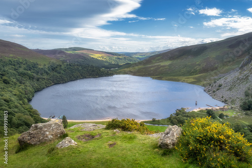 View on Lough Tay, called Guiness Lake with moored Viking longships and wooden village in Wicklow Mountains, Ireland