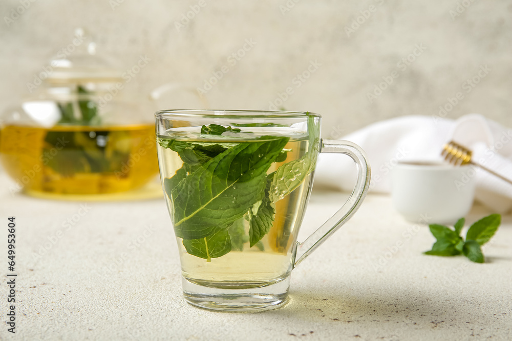 Teapot and cup of fresh mint tea on grunge light table Teapot and cup of fresh mint tea on grunge light table