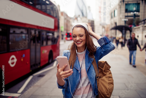 Young Caucasian woman using a smartphone while commuting on the streets of London UK