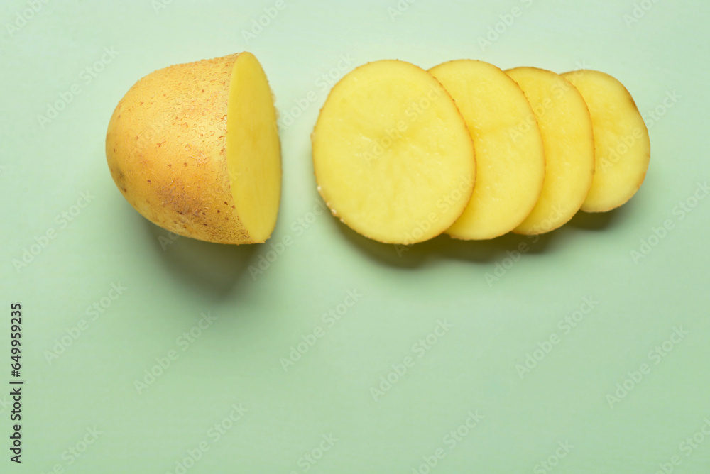 Raw cut potato on green background