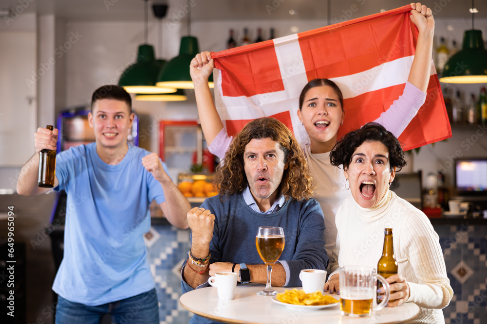 Obraz premium Joyful fans of the Denmark team celebrating the victory in the night bar