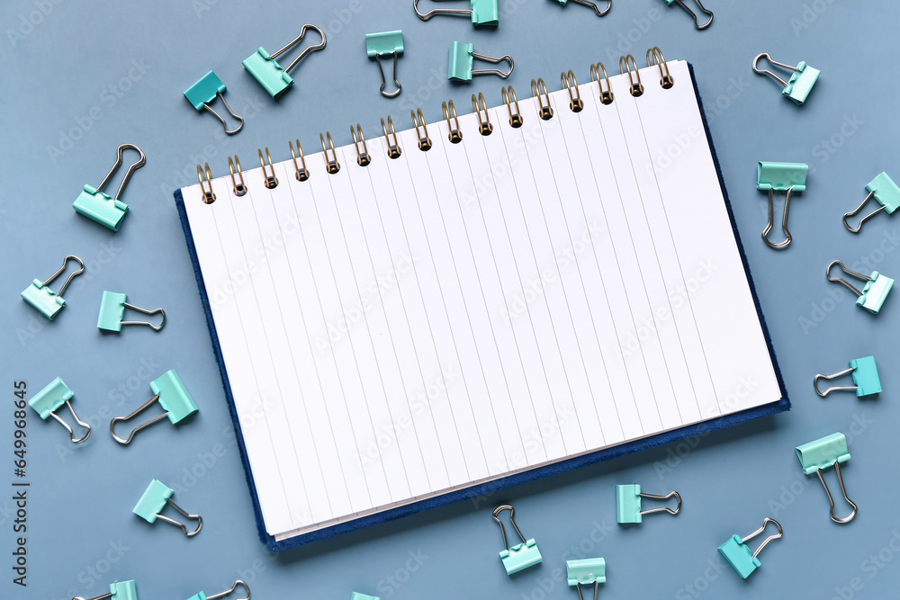 Notebook and paper clips on blue background Notebook and paper clips on blue background