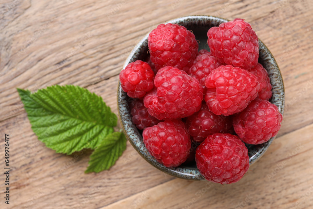Tasty ripe raspberries and green leaves on wooden table, top view Tasty ripe raspberries and green leaves on wooden table, top view