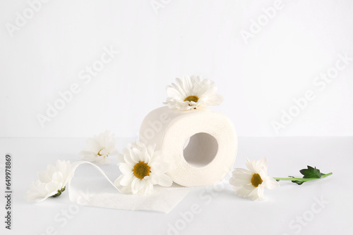 Toilet paper roll with chamomile flowers on white background