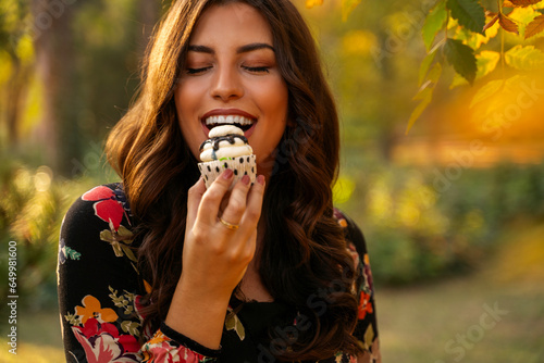 Amazingly pretty girl eating a cupcake in the park 